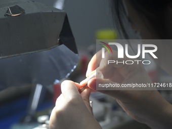 An employee processes medical endoscope lenses at the production workshop of Hangzhou HAoke Optoelectronic Instrument Co., LTD., located in...