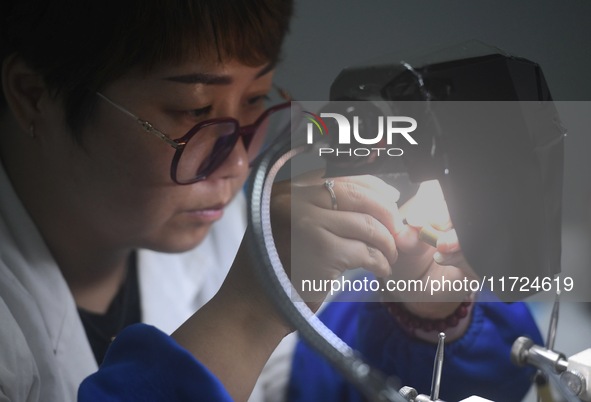 An employee processes medical endoscope lenses at the production workshop of Hangzhou HAoke Optoelectronic Instrument Co., LTD., located in...