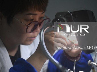 An employee processes medical endoscope lenses at the production workshop of Hangzhou HAoke Optoelectronic Instrument Co., LTD., located in...