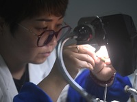 An employee processes medical endoscope lenses at the production workshop of Hangzhou HAoke Optoelectronic Instrument Co., LTD., located in...