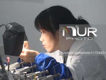 An employee processes medical endoscope lenses at the production workshop of Hangzhou HAoke Optoelectronic Instrument Co., LTD., located in...