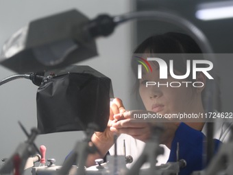 An employee processes medical endoscope lenses at the production workshop of Hangzhou HAoke Optoelectronic Instrument Co., LTD., located in...