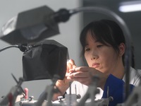 An employee processes medical endoscope lenses at the production workshop of Hangzhou HAoke Optoelectronic Instrument Co., LTD., located in...