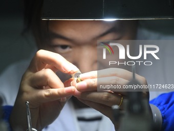 An employee processes medical endoscope lenses at the production workshop of Hangzhou HAoke Optoelectronic Instrument Co., LTD., located in...