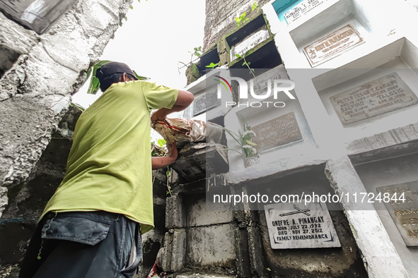 Erwin, in green, exhumes the remains buried inside the public cemetery in Antipolo City, Philippines, on October 31, 2024. A sack of human r...