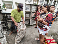 Erwin, in green, exhumes the remains buried inside the public cemetery in Antipolo City, Philippines, on October 31, 2024. A sack of human r...