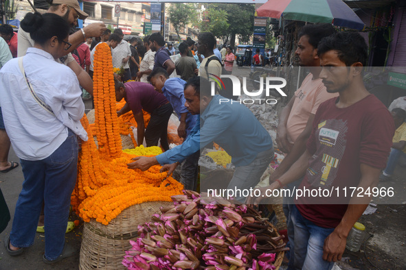 People buy flowers while sellers sell them at the roadside for home decorations on the occasion of 'Diwali', the Hindu festival of lights, i...