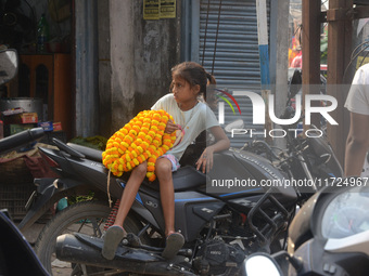 A seller's child sits on a scooter while people buy flowers from roadside sellers for home decorations on the occasion of 'Diwali,' the Hind...