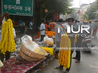 People buy flowers while sellers sell them at the roadside for home decorations on the occasion of 'Diwali', the Hindu festival of lights, i...