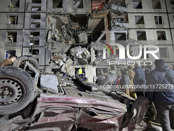 An overturned car is outside a section of a nine-storey residential building destroyed by a Russian glide bomb in Kharkiv, Ukraine, on Octob...