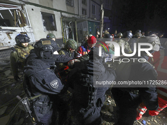 Rescuers and police officers carry an injured person at a section of a nine-storey residential building destroyed by a Russian glide bomb in...