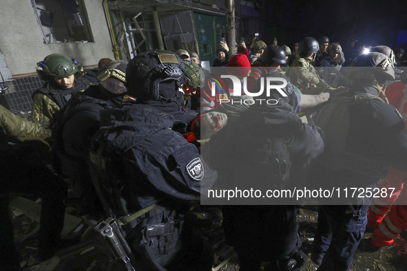 Rescuers and police officers carry an injured person at a section of a nine-storey residential building destroyed by a Russian glide bomb in...