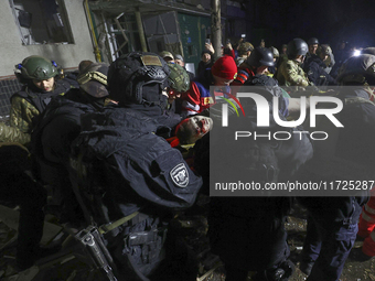 Rescuers and police officers carry an injured person at a section of a nine-storey residential building destroyed by a Russian glide bomb in...