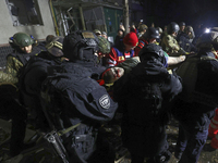 Rescuers and police officers carry an injured person at a section of a nine-storey residential building destroyed by a Russian glide bomb in...