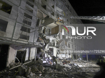 Rescuers use an aerial ladder to reach the affected floors of a nine-storey residential building damaged by a Russian glide bomb in Kharkiv,...