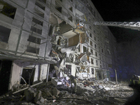 Rescuers use an aerial ladder to reach the affected floors of a nine-storey residential building damaged by a Russian glide bomb in Kharkiv,...