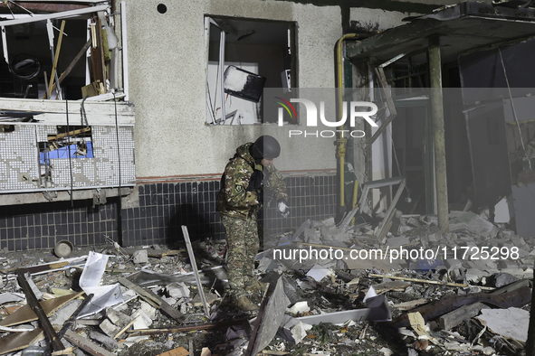 A serviceman with a torch searches the ground outside a section of a nine-story residential building destroyed by a Russian glide bomb in Kh...