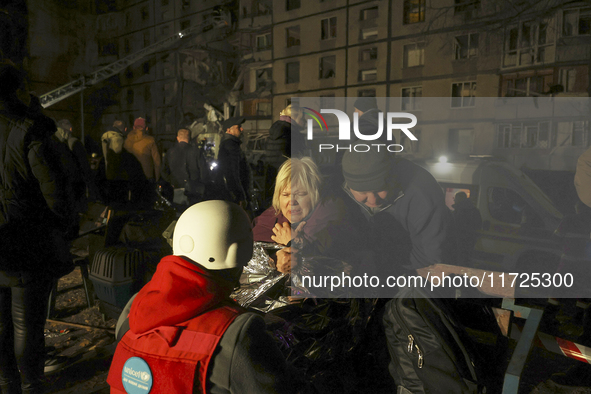 A woman wraps herself in a space blanket outside a section of a nine-storey residential building destroyed by a Russian glide bomb in Kharki...