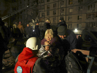 A woman wraps herself in a space blanket outside a section of a nine-storey residential building destroyed by a Russian glide bomb in Kharki...