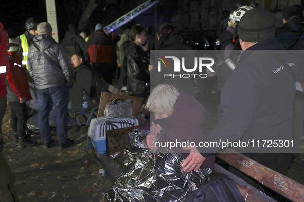 A woman wraps herself in a space blanket outside a section of a nine-storey residential building destroyed by a Russian glide bomb in Kharki...