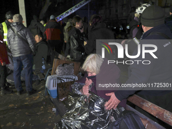 A woman wraps herself in a space blanket outside a section of a nine-storey residential building destroyed by a Russian glide bomb in Kharki...