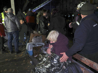 A woman wraps herself in a space blanket outside a section of a nine-storey residential building destroyed by a Russian glide bomb in Kharki...