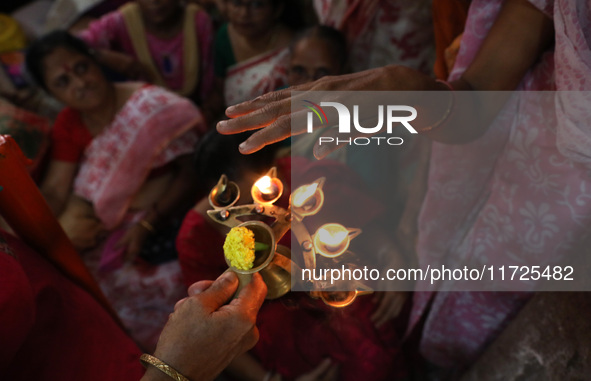 Devotees take blessings from an oil lamp after Ridhima Jana, a 9-year-old girl dressed as a Kumari, is worshiped by devotees during rituals...