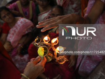 Devotees take blessings from an oil lamp after Ridhima Jana, a 9-year-old girl dressed as a Kumari, is worshiped by devotees during rituals...