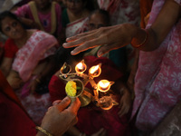 Devotees take blessings from an oil lamp after Ridhima Jana, a 9-year-old girl dressed as a Kumari, is worshiped by devotees during rituals...