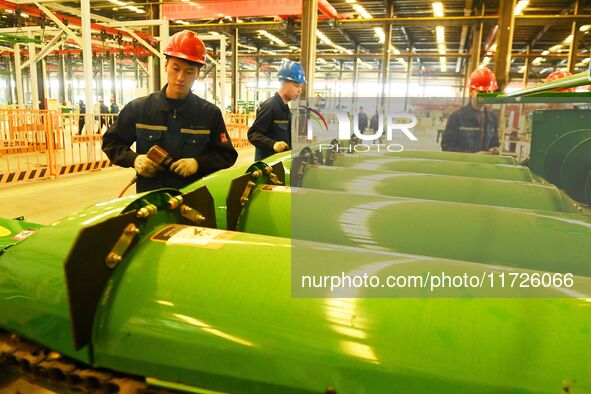 Construction workers assemble agricultural machinery at Jiufang Taihe International Heavy Industries (Qingdao) Co LTD in Qingdao, China, on...