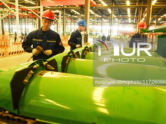 Construction workers assemble agricultural machinery at Jiufang Taihe International Heavy Industries (Qingdao) Co LTD in Qingdao, China, on...