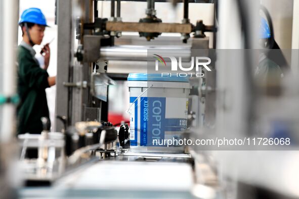 Workers produce lubricating oil on a production line at Qingdao Compton Technology Co LTD in Qingdao, Shandong province, China, on October 3...