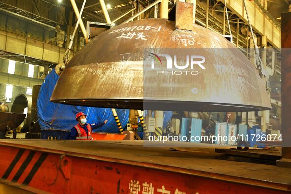 A construction worker directs the lifting of engineering components at Lanshi Heavy Machinery Co LTD in Qingdao, China, on October 31, 2024....