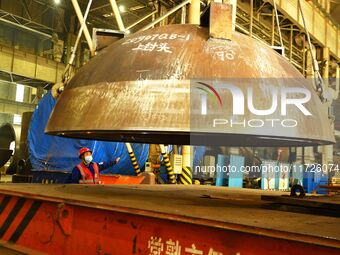 A construction worker directs the lifting of engineering components at Lanshi Heavy Machinery Co LTD in Qingdao, China, on October 31, 2024....