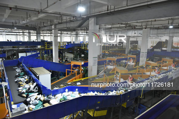 Workers use automatic sorting equipment to sort parcels at the Fuyang Mail Processing Center of China Post in Fuyang, China, on October 23,...