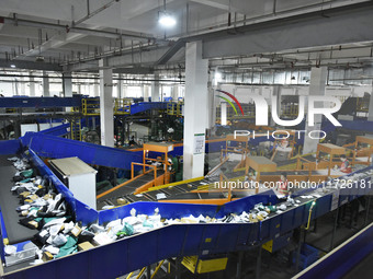 Workers use automatic sorting equipment to sort parcels at the Fuyang Mail Processing Center of China Post in Fuyang, China, on October 23,...