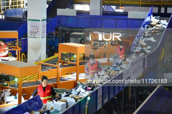 Workers use automatic sorting equipment to sort parcels at the Fuyang Mail Processing Center of China Post in Fuyang, China, on October 23,...