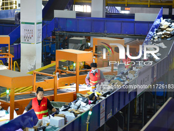 Workers use automatic sorting equipment to sort parcels at the Fuyang Mail Processing Center of China Post in Fuyang, China, on October 23,...