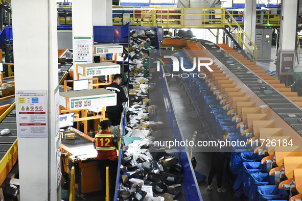 Workers use automatic sorting equipment to sort parcels at the Fuyang Mail Processing Center of China Post in Fuyang, China, on October 23,...