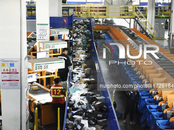 Workers use automatic sorting equipment to sort parcels at the Fuyang Mail Processing Center of China Post in Fuyang, China, on October 23,...