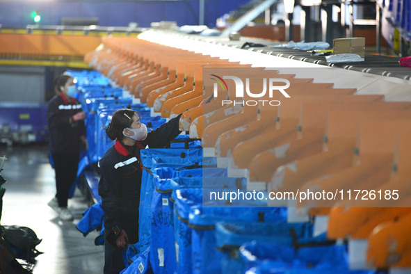 Workers use automatic sorting equipment to sort parcels at the Fuyang Mail Processing Center of China Post in Fuyang, China, on October 23,...