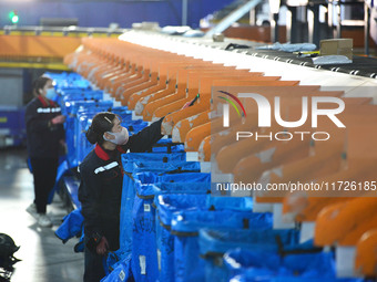 Workers use automatic sorting equipment to sort parcels at the Fuyang Mail Processing Center of China Post in Fuyang, China, on October 23,...