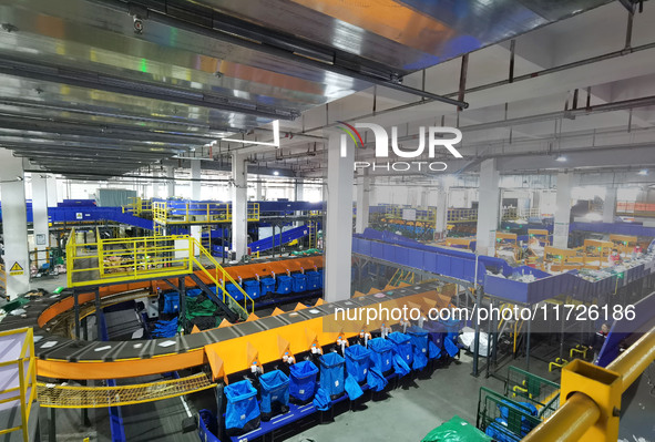 Workers use automatic sorting equipment to sort parcels at the Fuyang Mail Processing Center of China Post in Fuyang, China, on October 23,...