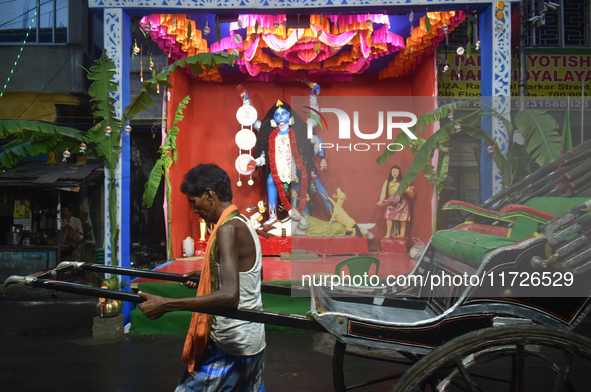 A hand-pulled rickshaw passes next to a Kali idol in Kolkata, India, on October 31, 2024. 