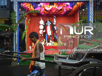 A hand-pulled rickshaw passes next to a Kali idol in Kolkata, India, on October 31, 2024. (