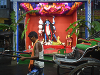 A hand-pulled rickshaw passes next to a Kali idol in Kolkata, India, on October 31, 2024. (