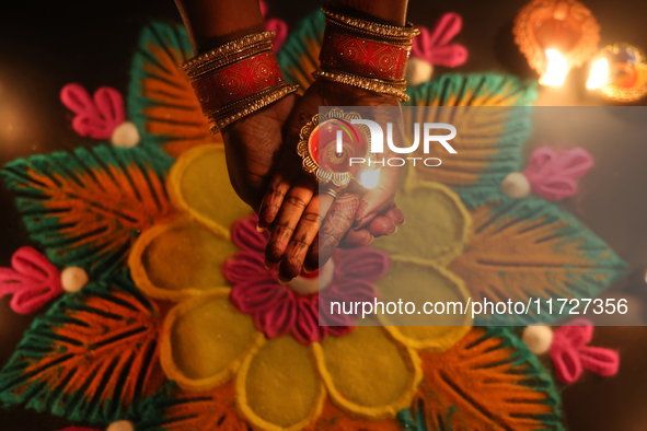 A Hindu devotee holds a diya (small clay lamp) by a rangoli design during the festival of Diwali at a Hindu temple in Toronto, Ontario, Cana...