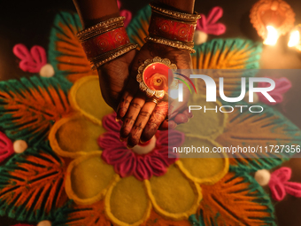 A Hindu devotee holds a diya (small clay lamp) by a rangoli design during the festival of Diwali at a Hindu temple in Toronto, Ontario, Cana...