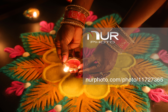 A Hindu devotee places a diya (small clay lamp) by a rangoli design during the festival of Diwali at a Hindu temple in Toronto, Ontario, Can...