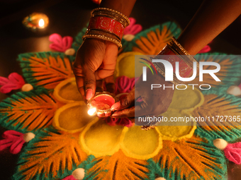 A Hindu devotee places a diya (small clay lamp) by a rangoli design during the festival of Diwali at a Hindu temple in Toronto, Ontario, Can...